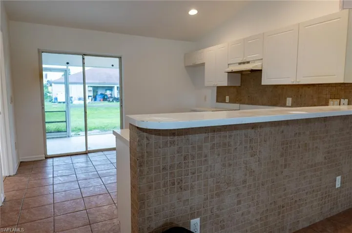 Kitchen featuring white cabinetry, a peninsula, light countertops, decorative backsplash, and recessed lighting