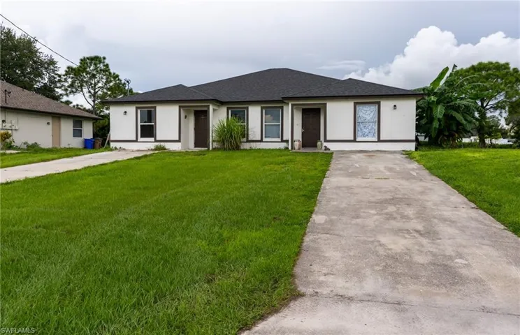 View of front of property with concrete driveway, a front yard, stucco siding, and roof with shingles