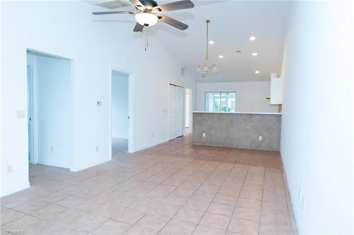 Unfurnished room featuring light tile patterned floors, high vaulted ceiling, recessed lighting, a chandelier, and ceiling fan