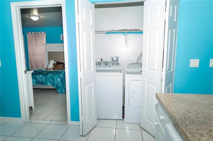 Laundry area featuring light tile patterned floors and washing machine and dryer