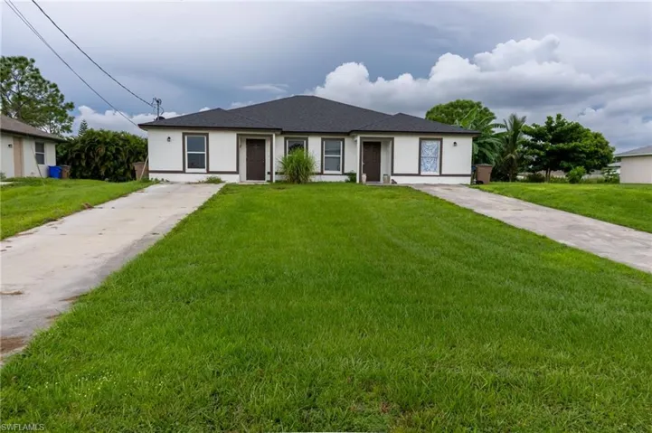 Ranch-style home featuring stucco siding, a front yard, concrete driveway, and a shingled roof