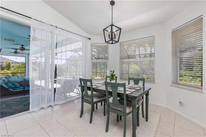 Dining space featuring light tile patterned flooring, a ceiling fan, vaulted ceiling, healthy amount of natural light, and a chandelier