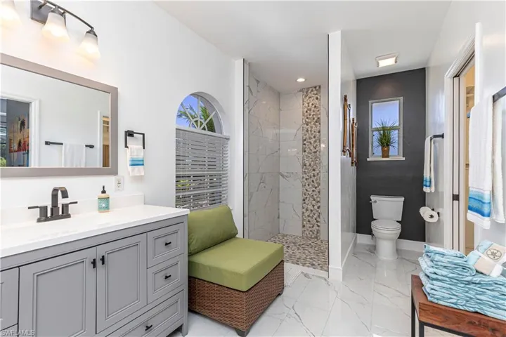 Full bathroom featuring vanity, a walk in shower, and light marble finish flooring