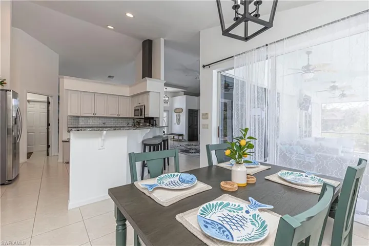 Dining area with light tile patterned flooring, a ceiling fan, and a chandelier