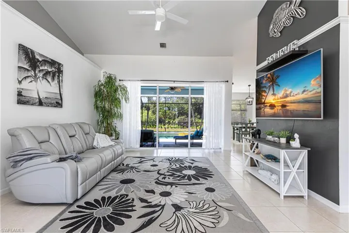 Living room featuring ceiling fan, a sunroom, vaulted ceiling, and light tile patterned floors