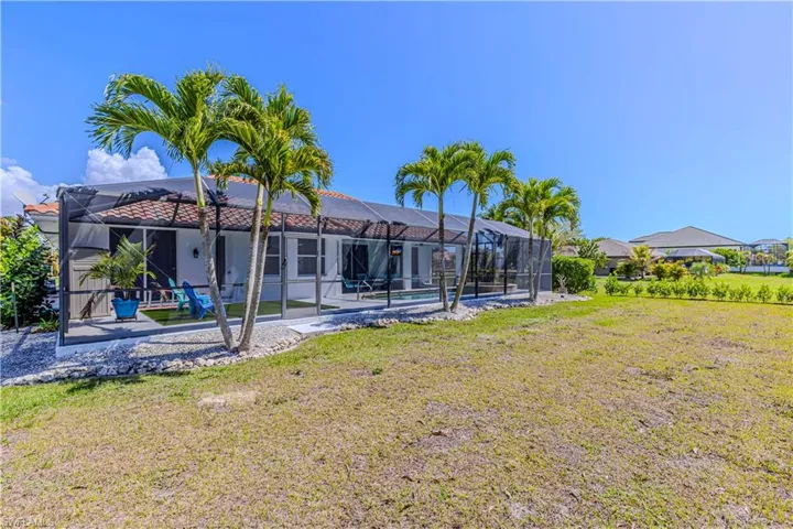 Rear view of property with a sunroom, glass enclosure, an outdoor pool, and a yard