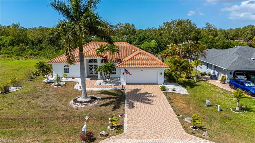 Mediterranean / spanish house featuring an attached garage, decorative driveway, a front yard, a tiled roof, and stucco siding