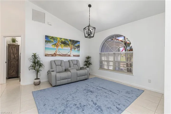 Living area with lofted ceiling, light tile patterned floors, and hanging lights