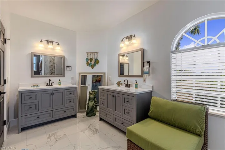 Bathroom featuring two vanities and light marble finish flooring