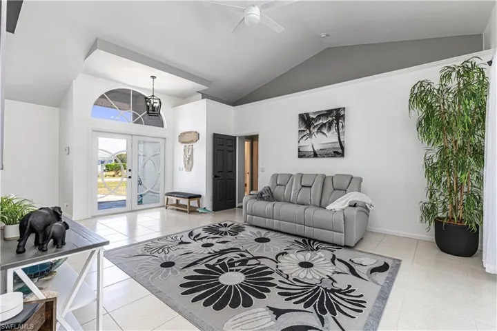 Living room with a ceiling fan, a high ceiling, and french doors