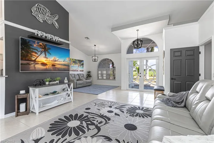 Living area featuring light tile patterned floors, french doors, a chandelier, and lofted ceiling