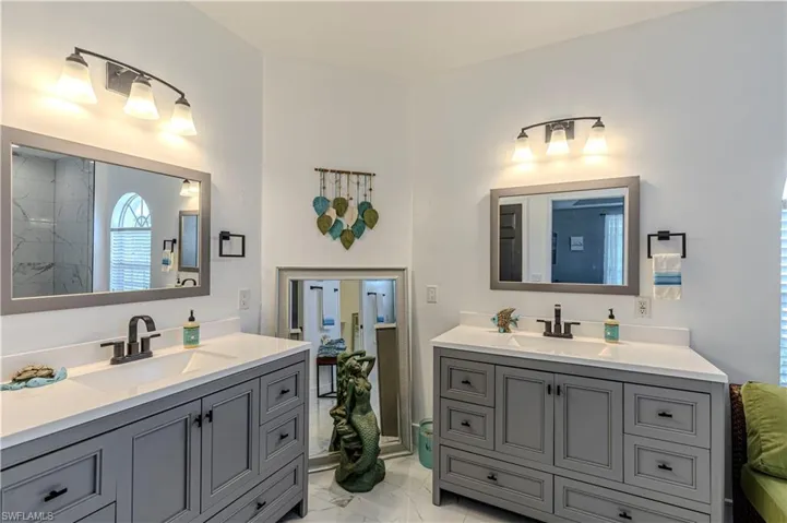 Bathroom with two vanities and light marble finish floors