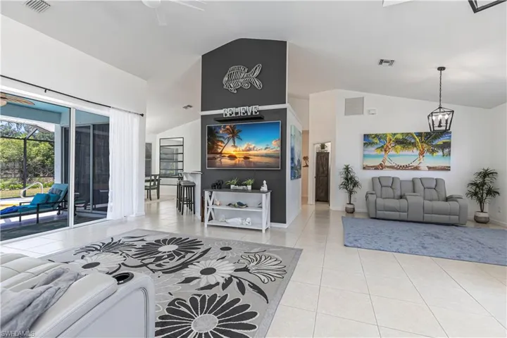 Living room with ceiling fan, vaulted ceiling, light tile patterned floors, and suspended lighting