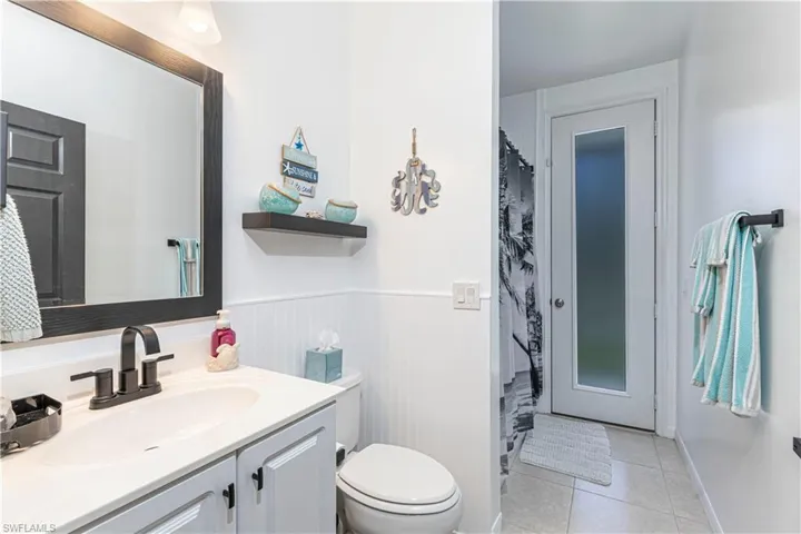 Full bath with vanity, a shower with curtain, wainscoting, and light tile patterned floors