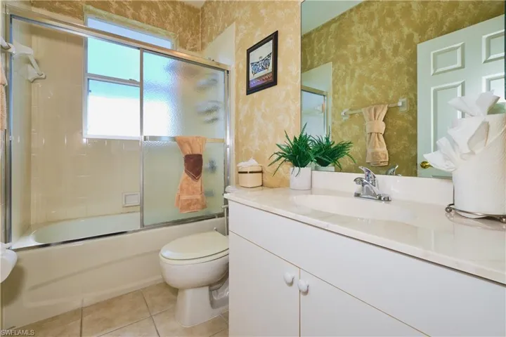Bathroom featuring shower / bath combination with glass door, vanity, and light tile patterned flooring