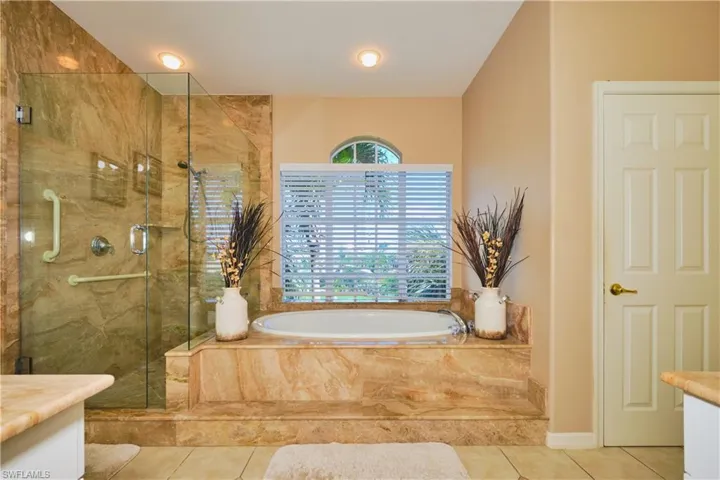 Full bath featuring vanity, a garden tub, a marble finish shower, and tile patterned floors