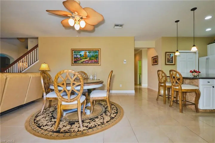 Dining area featuring light tile patterned flooring, ceiling fan, recessed lighting, and stairway