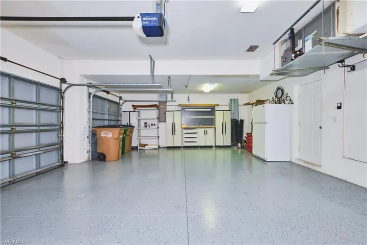 Garage featuring freestanding refrigerator and a garage door opener