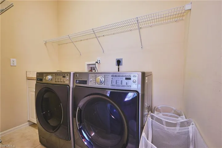 Washroom with washer and clothes dryer and tile patterned floors