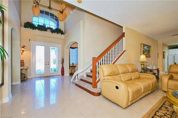 Entryway with french doors, a towering ceiling, arched walkways, stairway, and light tile patterned floors