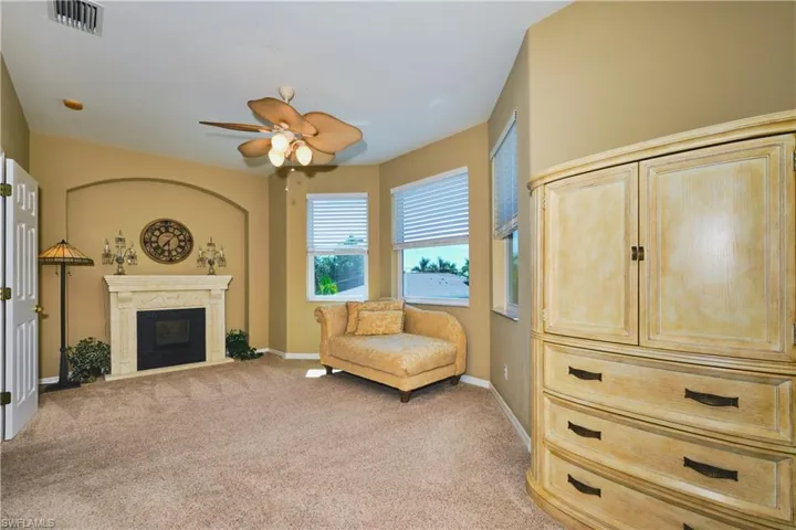 Sitting room with light colored carpet, a fireplace, and a ceiling fan