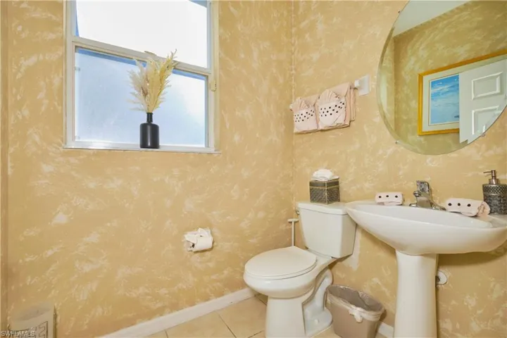 Half bath with tile patterned floors and wallpapered walls
