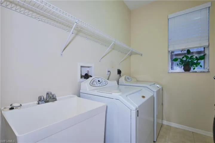 Laundry area with light tile patterned flooring and separate washer and dryer