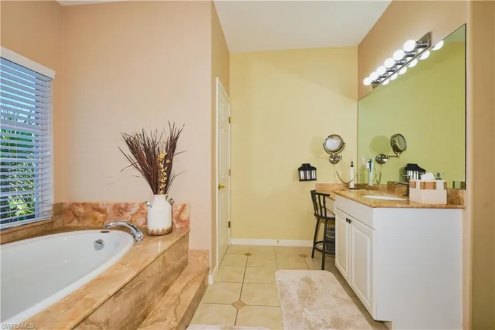 Bathroom featuring vanity, a garden tub, and light tile patterned floors