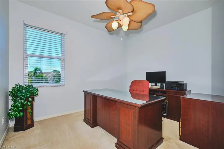 Office area with light colored carpet and a ceiling fan