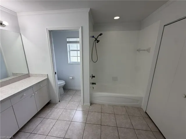 Bathroom featuring a full vanity with a built-in mirror, an integrated tub and shower, tile flooring, and crown molding