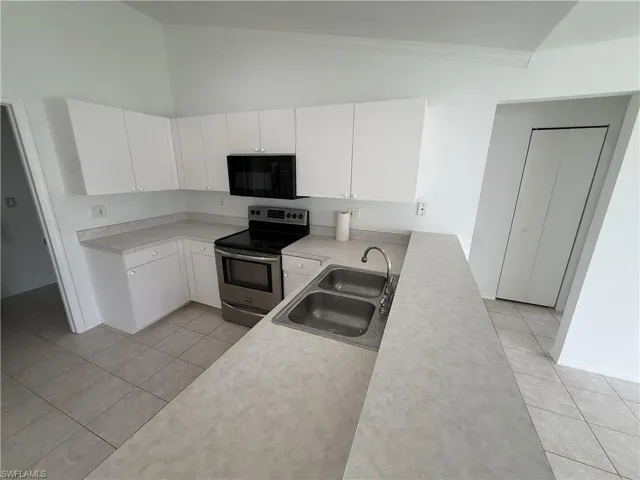 Kitchen featuring white cabinetry, light countertops, a stainless steel range, and an over-the-range microwave
