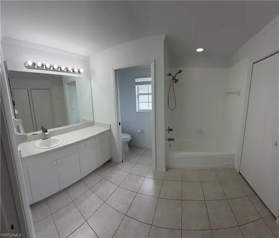 Spacious bathroom featuring a long vanity with an integrated sink, a large wall-mounted mirror, and a full bathtub with an overhead shower