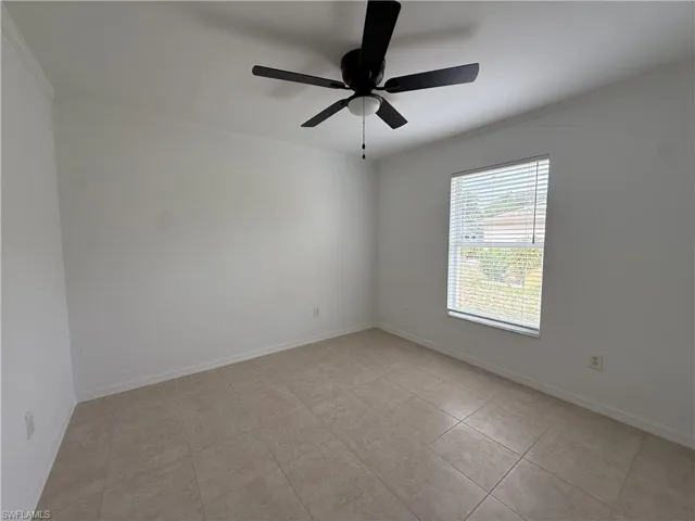 Room featuring neutral-toned tile flooring, white baseboards, and a window with horizontal blinds