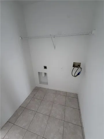 Utility closet featuring neutral tile flooring, white wire shelving, and appliance hookups