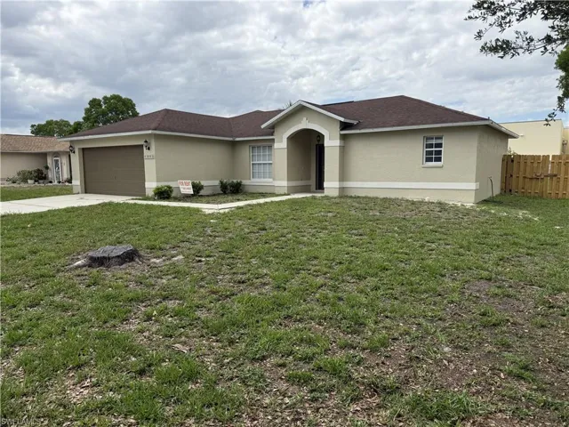 Single-story residence featuring a two-car garage, front entry archway, and a fenced side yard