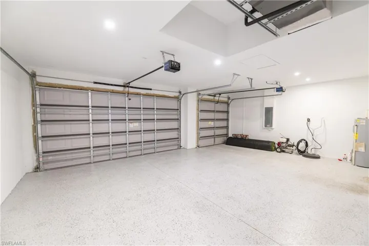 Garage featuring water heater, electric panel, and a garage door opener