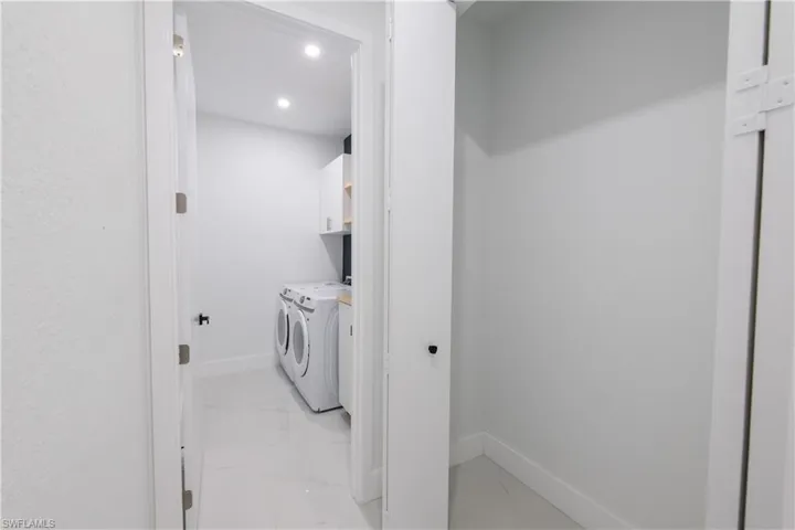 Laundry room with washer and dryer, light marble finish floors, and recessed lighting