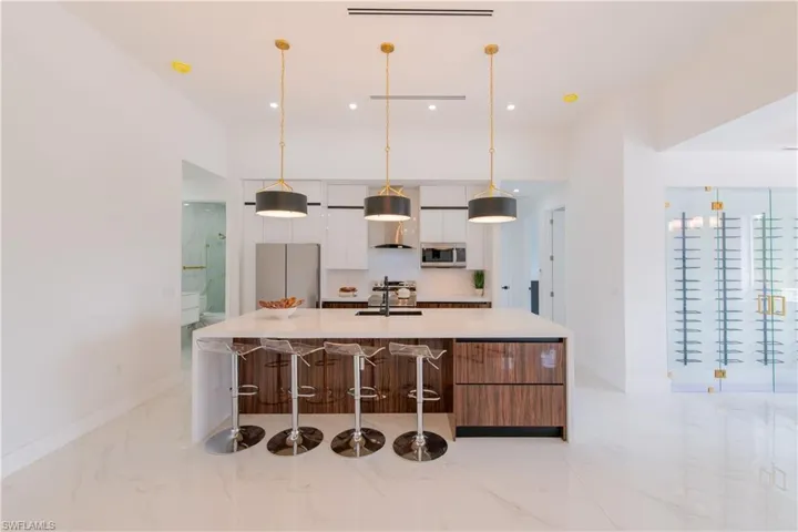 Kitchen featuring a large island, modern cabinets, light marble finish floors, a kitchen bar, and freestanding refrigerator