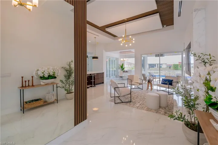 Living room with hanging lights, light marble finish floors, and a high ceiling