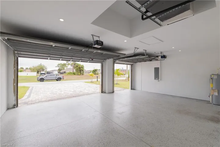 Garage with water heater, recessed lighting, electric panel, and a garage door opener