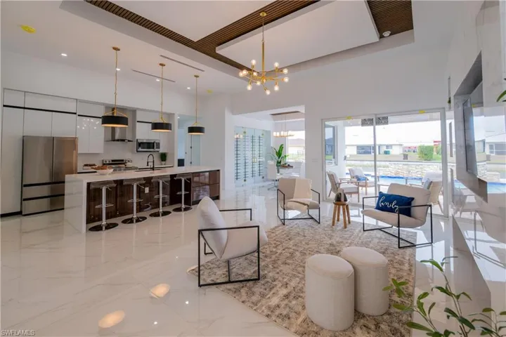 Living room with suspended lighting, a tray ceiling, and light marble finish floors