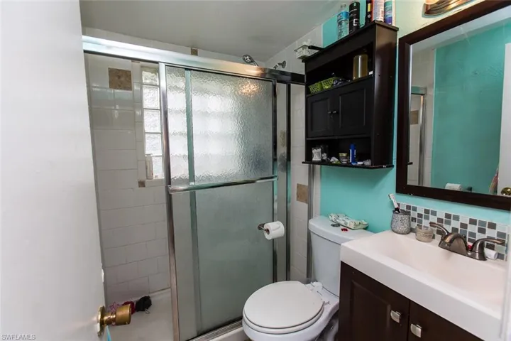 Bathroom featuring tile walls, walk in shower, decorative backsplash, toilet, and vanity