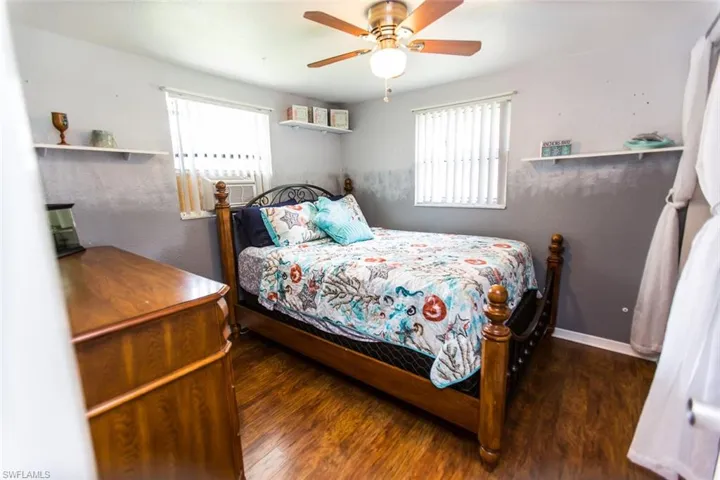 Bedroom with dark wood-type flooring, ceiling fan, and multiple windows