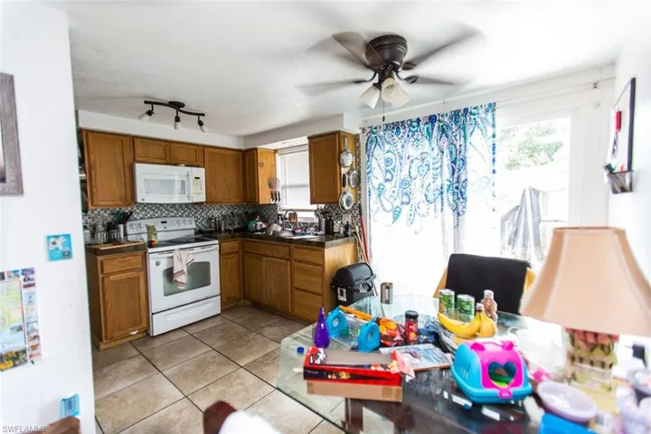 Kitchen featuring ceiling fan, rail lighting, decorative backsplash, white appliances, and light tile patterned floors