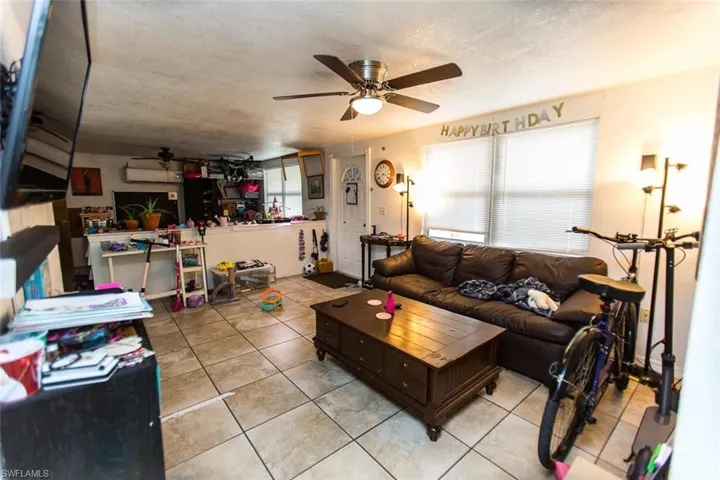 Living room featuring light tile patterned flooring, a textured ceiling, and ceiling fan