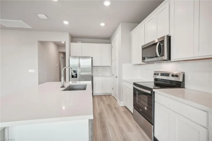 Kitchen featuring white cabinets, sink, appliances with stainless steel finishes, and light hardwood / wood-style floors