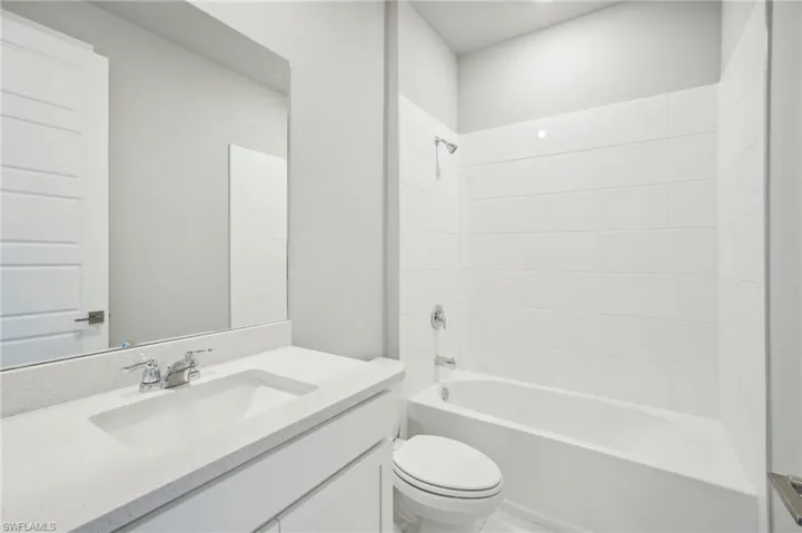 Full bathroom featuring tiled shower / bath combo, vanity, and toilet