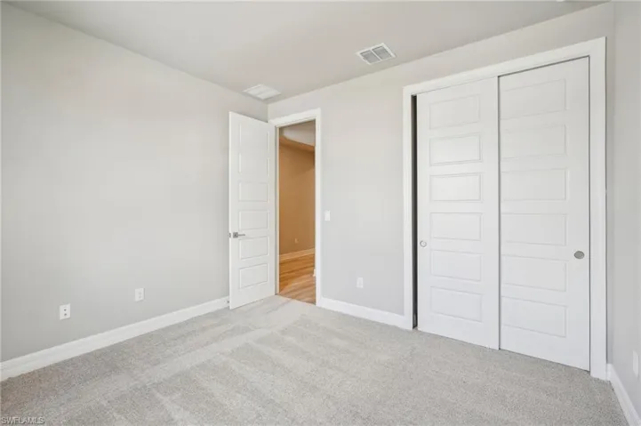 Unfurnished bedroom with light colored carpet and a closet