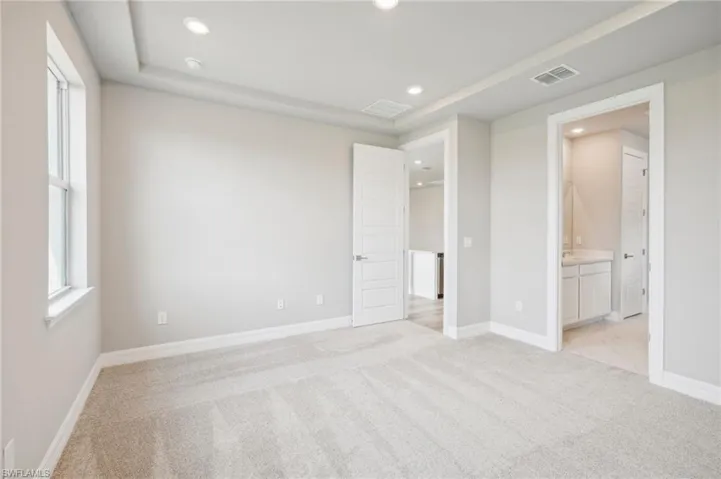 Unfurnished bedroom featuring light carpet and connected bathroom