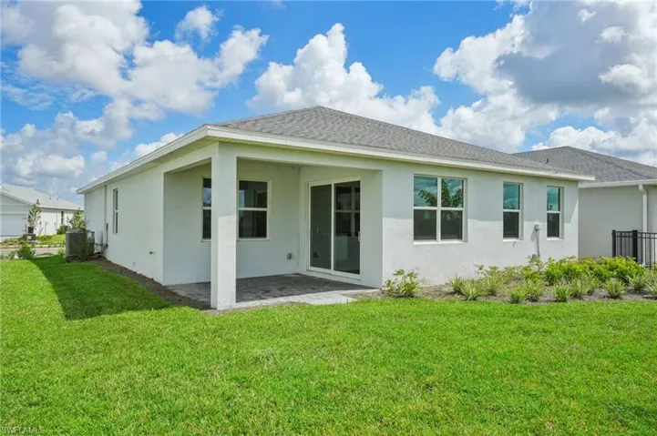 Rear view of property featuring a lawn, cooling unit, and a patio
